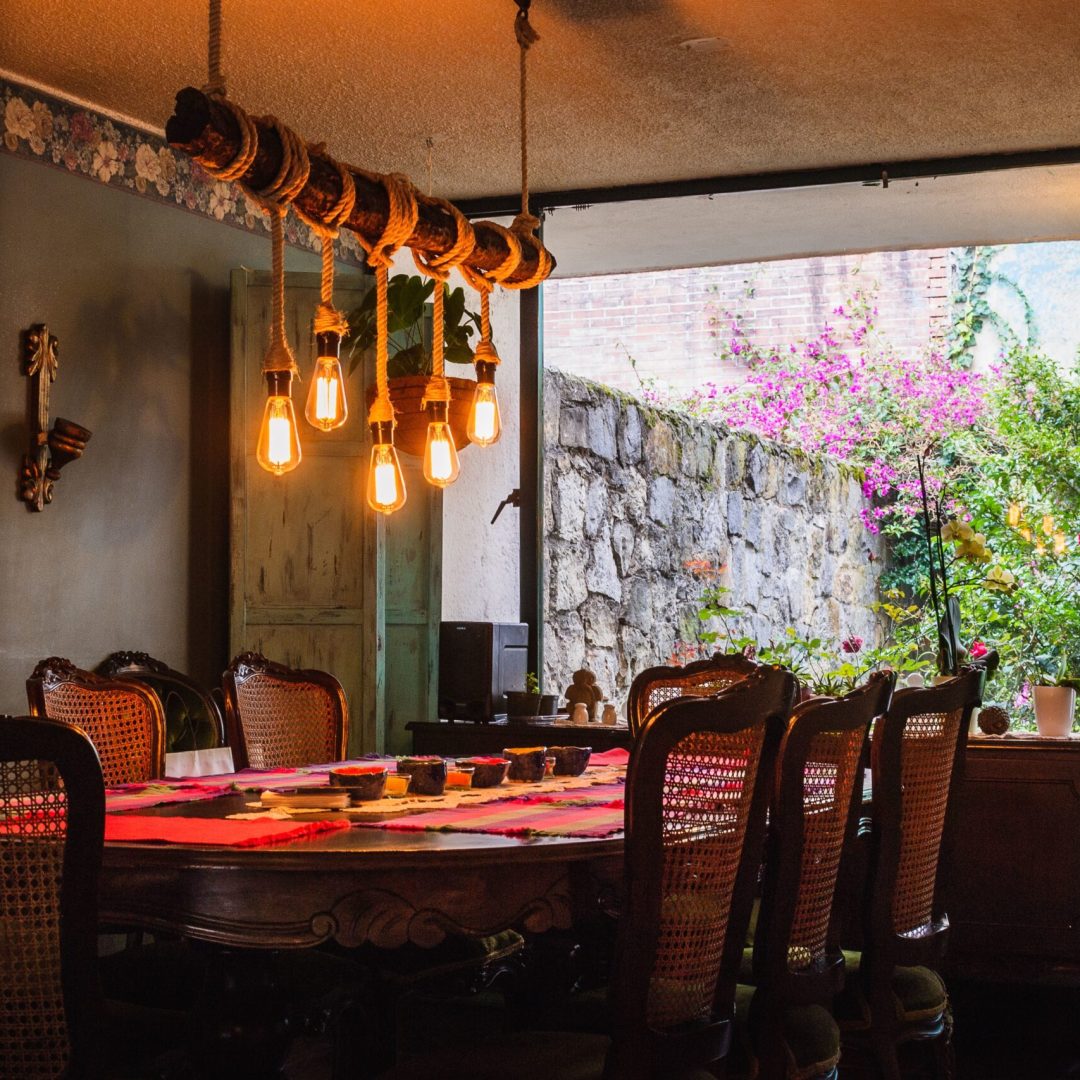 A rustic chandelier made of bulbs and ropes over a dining table in a vintage kitchen