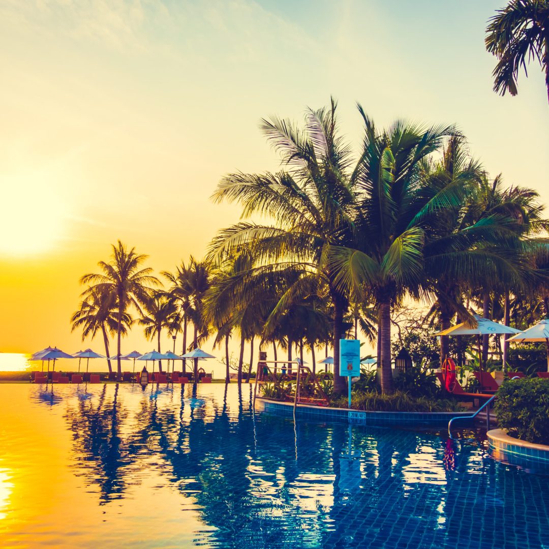 Silhouette palm tree with umbrella and chair around beautiful luxury swimming pool in hotel resort at Sunset time - Vintage Filter and Boost up Color Processing