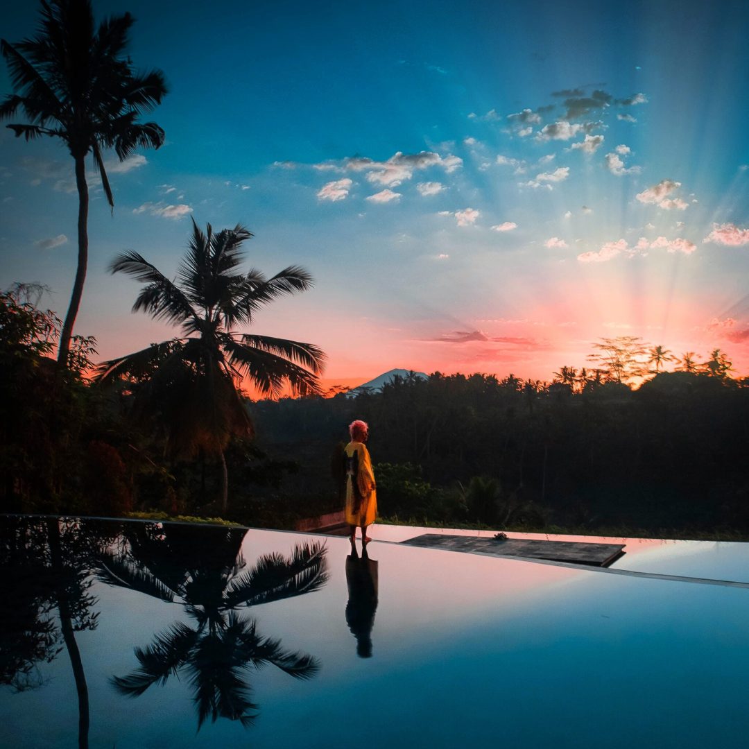 woman-standing-by-poolside-against-sky-sunset