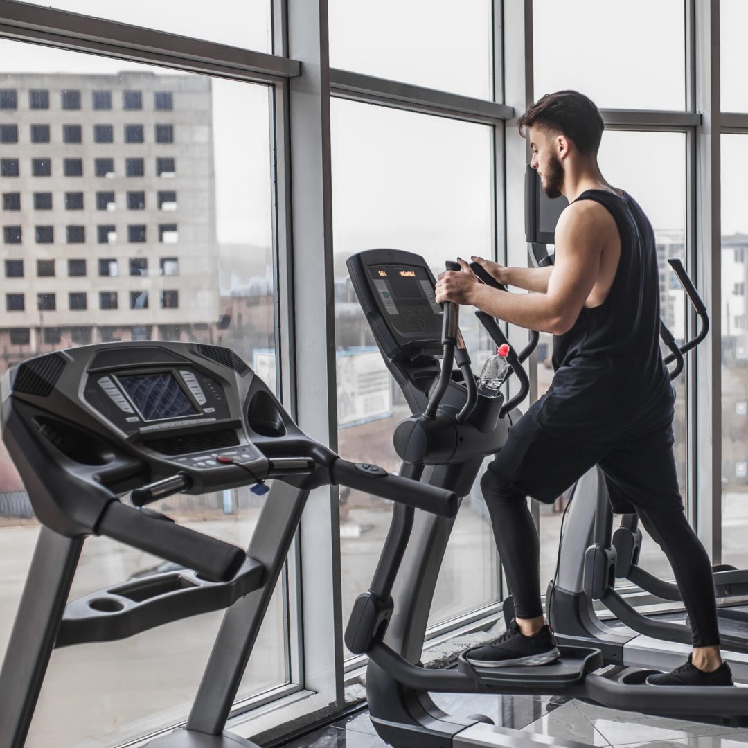 Photo of young bodybuilder running cardio workout and looking at the gym window.